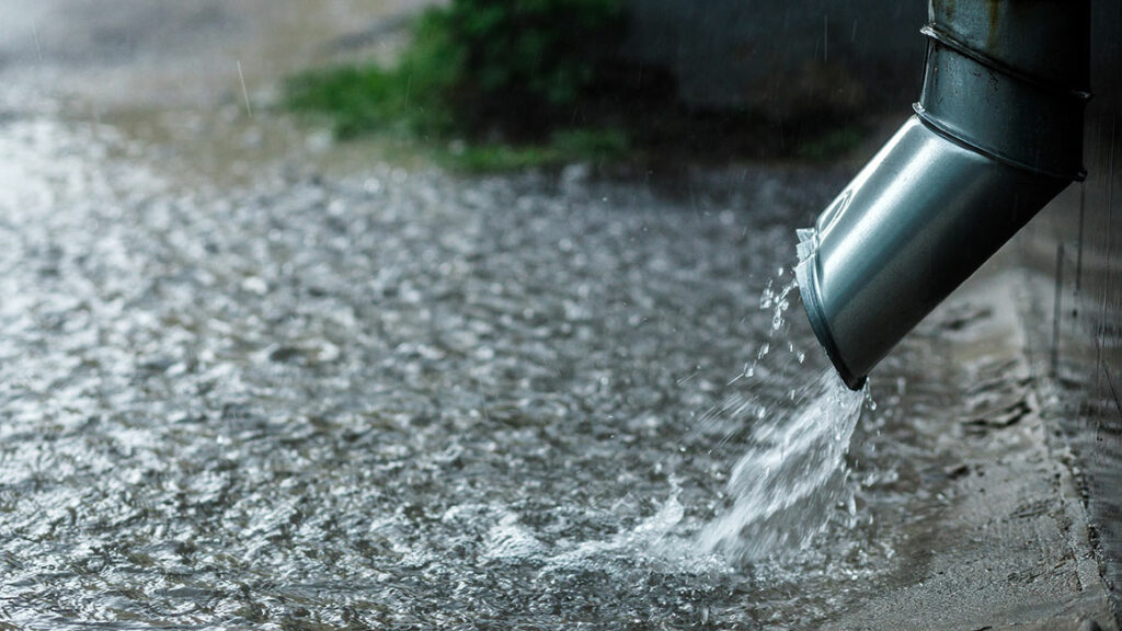 Aus einem Fallrohr fliest viel Wasser, das für die Regenwassernutzung gesammelt werden könnte