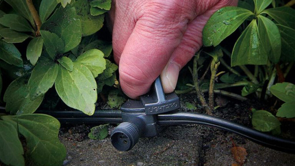 Handwerker beim Verbinden von Kabeln im Garten. Die Kabel sind Teil des Lighpro-Sortiments.