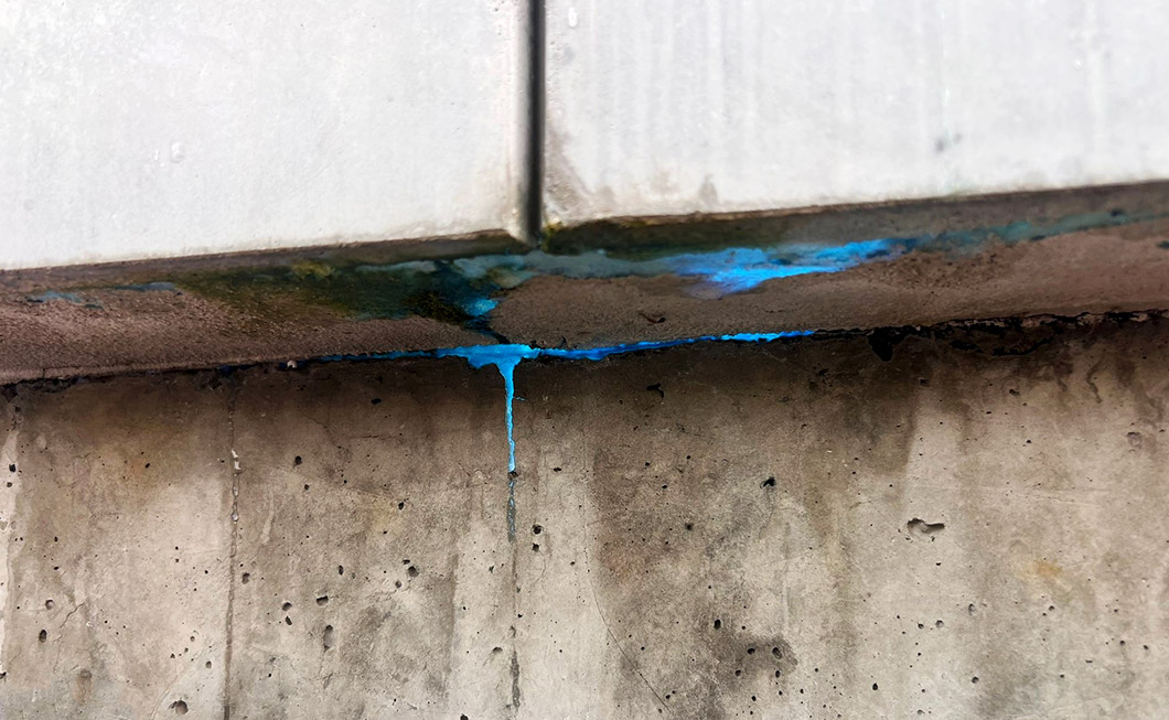 Blaue UV-Tracersubstanz trirtt aus einer Betonwand