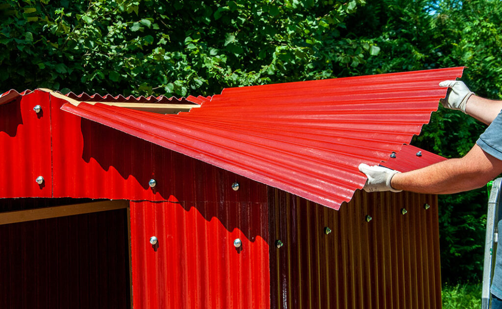 Roter Geräteschuppen im Aufbau - Anbringen des Dachs