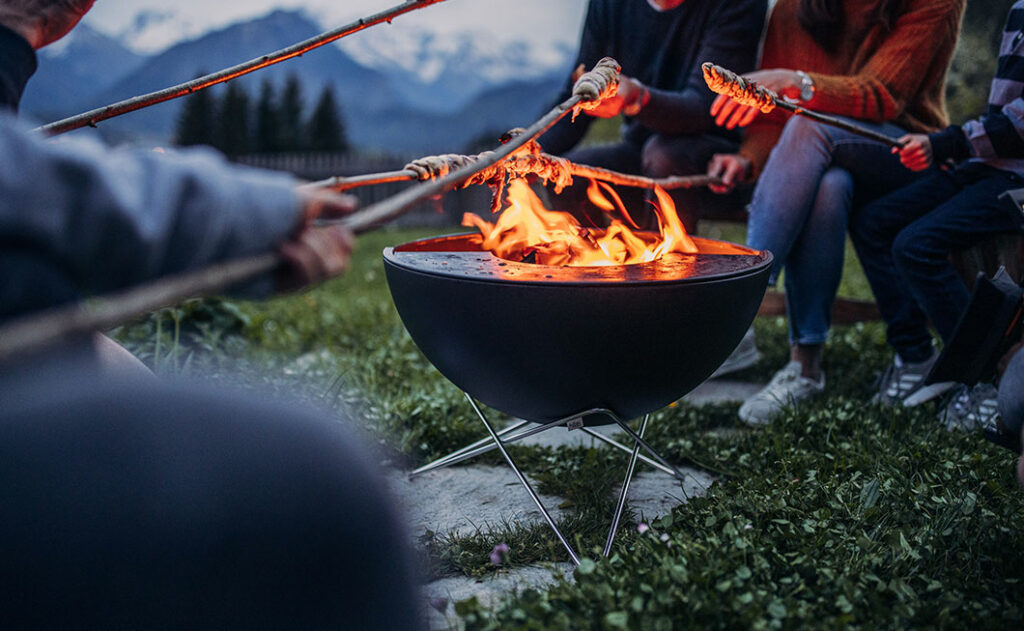 Feuerschale mit Menschen die drumherums sitzen beim Eindunkeln