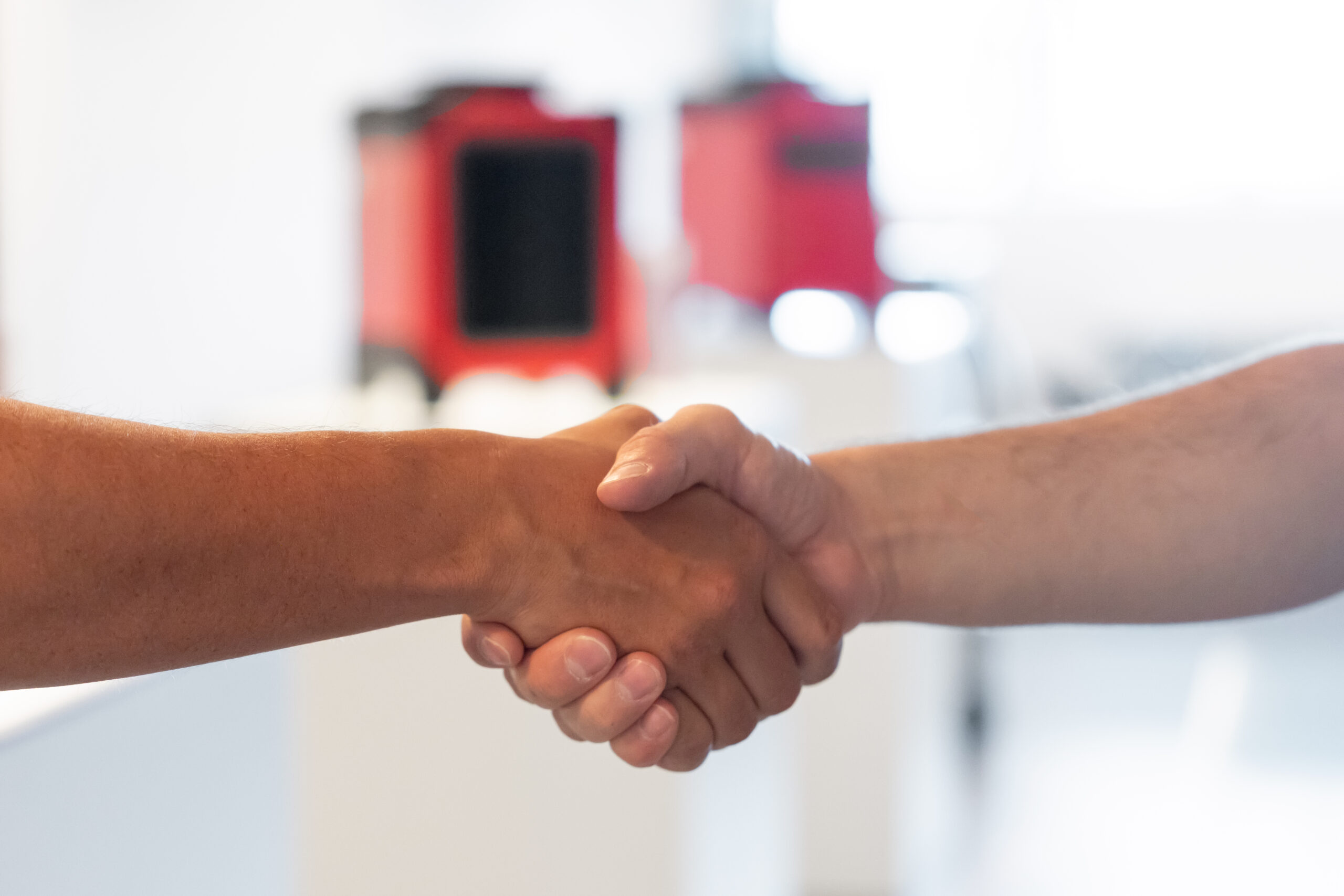 Vertragsabschluss beim Leasing – zwei Personen geben sich die Hand vor fapatrock-Geräten.