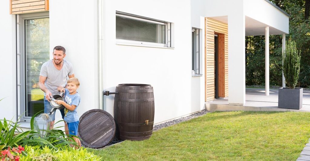 Vater und Sohn giessen mit einer Giesskanne den Garten.